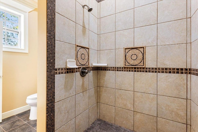 bathroom featuring a tile shower and toilet