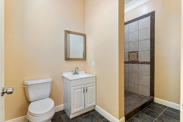 bathroom with tile patterned flooring, vanity, a tile shower, and toilet