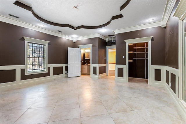 empty room featuring crown molding, a raised ceiling, a textured ceiling, and light tile patterned flooring