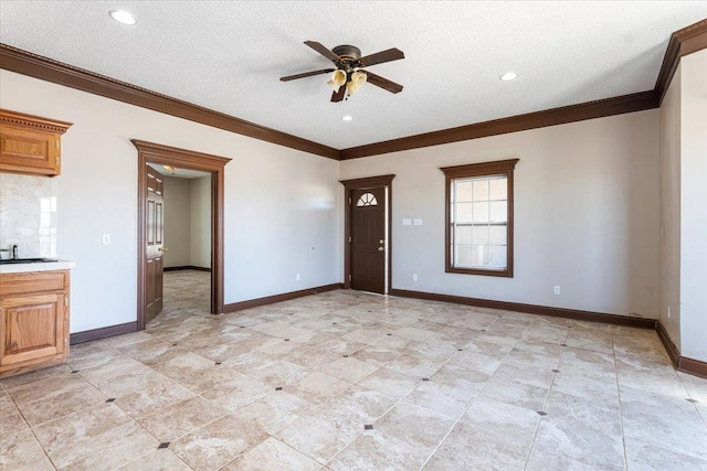 interior space featuring ornamental molding, sink, ceiling fan, and a textured ceiling