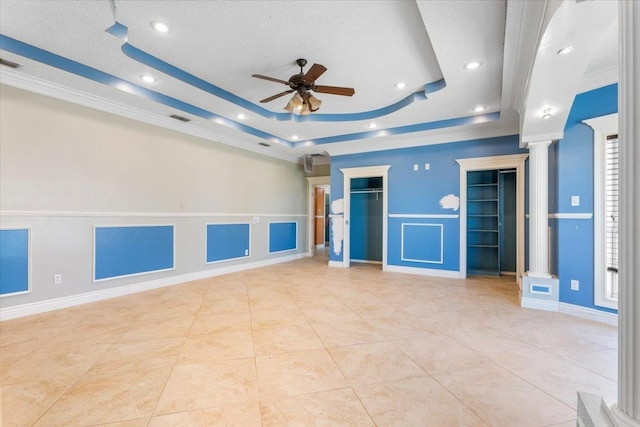 unfurnished living room with ornate columns, light tile patterned flooring, ceiling fan, a raised ceiling, and crown molding