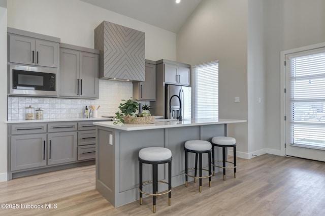 5713 119th St, Lubbock, TX 79424 - kitchen with gray cabinetry, built in microwave, high vaulted ceiling, backsplash, and a kitchen island with sink