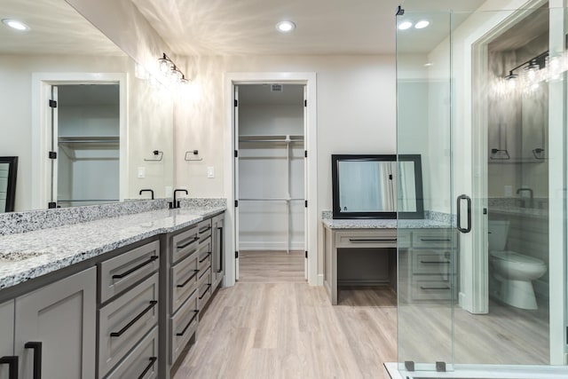 5713 119th St, Lubbock, TX 79424 - full bath with double vanity, toilet, wood finished floors, a shower stall, and recessed lighting