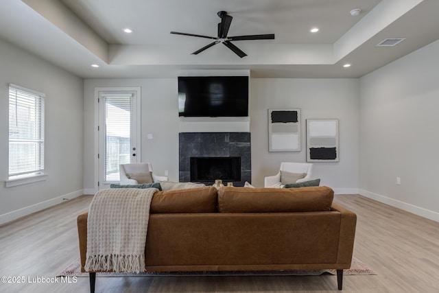 5713 119th St, Lubbock, TX 79424 - living room featuring a tiled fireplace, light wood-style flooring, a raised ceiling, baseboards, and recessed lighting