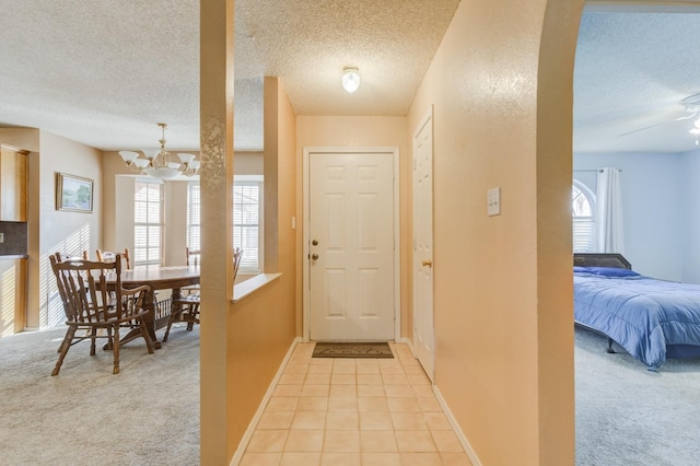 tiled entrance foyer featuring ceiling fan with notable chandelier and a textured ceiling