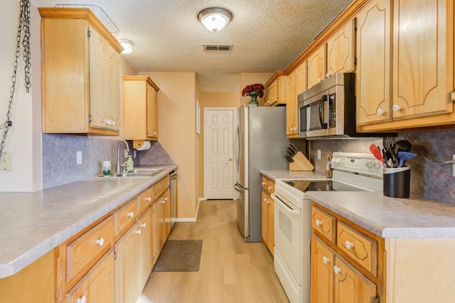 kitchen featuring sink, decorative backsplash, light hardwood / wood-style floors, stainless steel appliances, and a textured ceiling