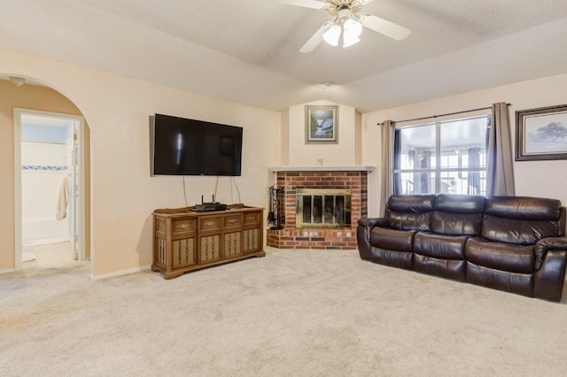 carpeted living room with vaulted ceiling, ceiling fan, and a fireplace