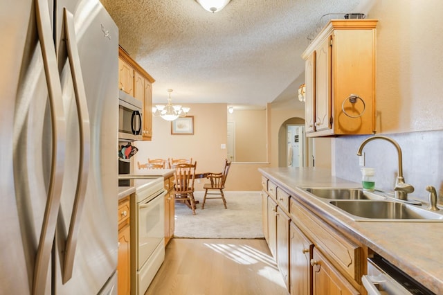 kitchen with pendant lighting, sink, stainless steel appliances, and a textured ceiling