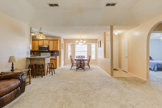 carpeted dining area with a textured ceiling and a notable chandelier