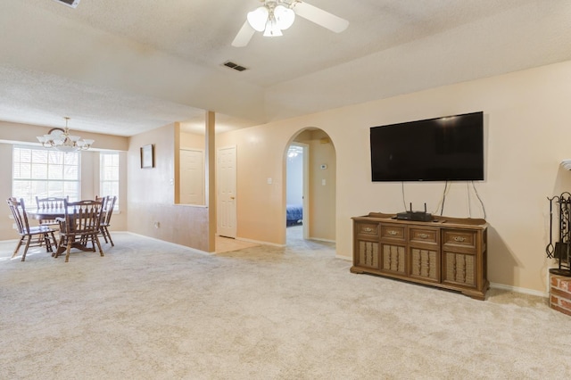 carpeted living room with ceiling fan with notable chandelier and a textured ceiling