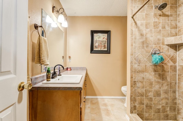 bathroom with vanity, a textured ceiling, toilet, and tiled shower