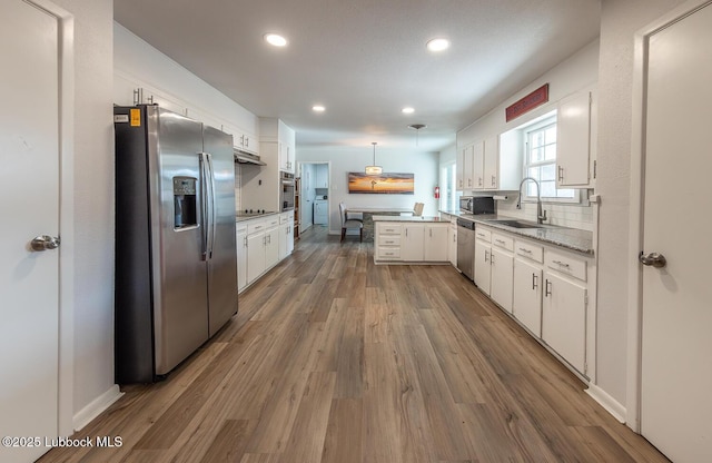 3410 53rd St, Lubbock, TX 79413 - kitchen with stainless steel appliances, a peninsula, white cabinets, wood finished floors, and recessed lighting