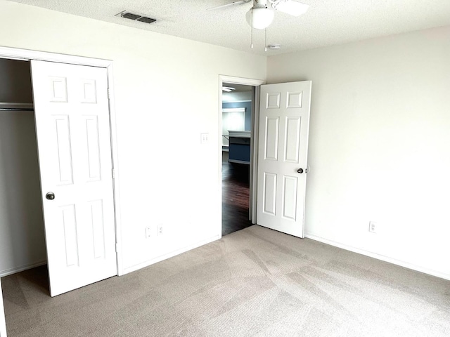 unfurnished bedroom with light colored carpet, a textured ceiling, ceiling fan, and a closet