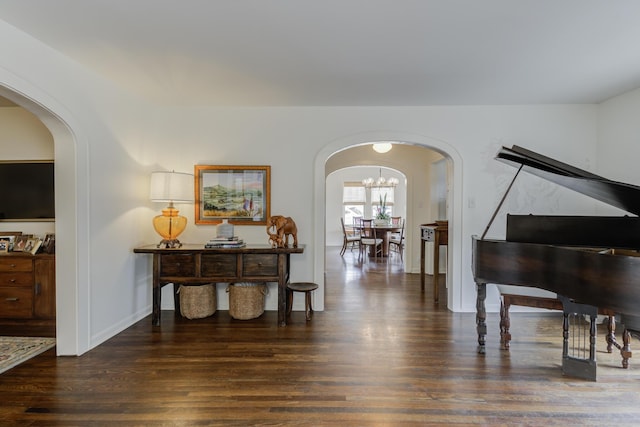 interior space with arched walkways, baseboards, an inviting chandelier, and wood finished floors