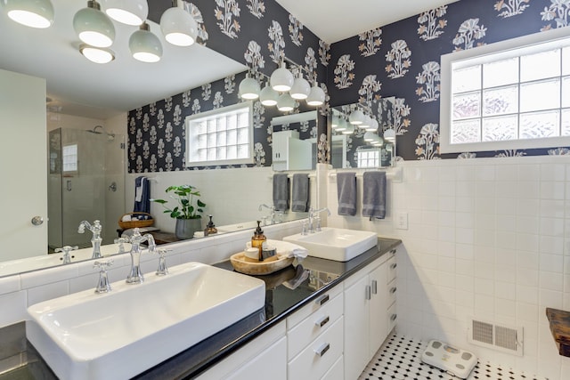 full bathroom featuring a sink, visible vents, tile walls, and wallpapered walls