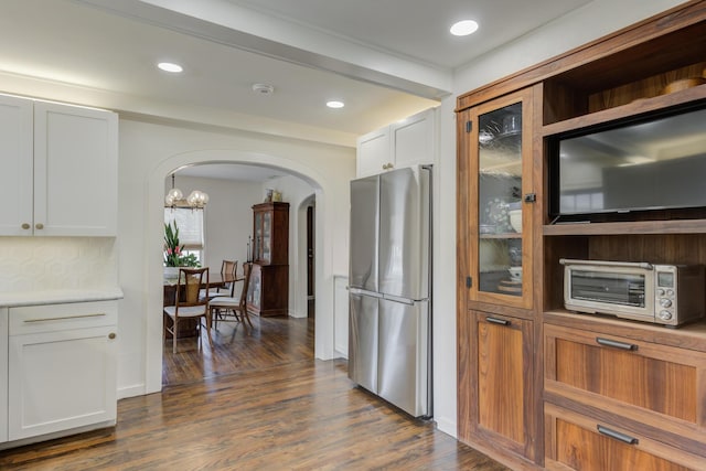 kitchen featuring a toaster, arched walkways, freestanding refrigerator, and dark wood finished floors