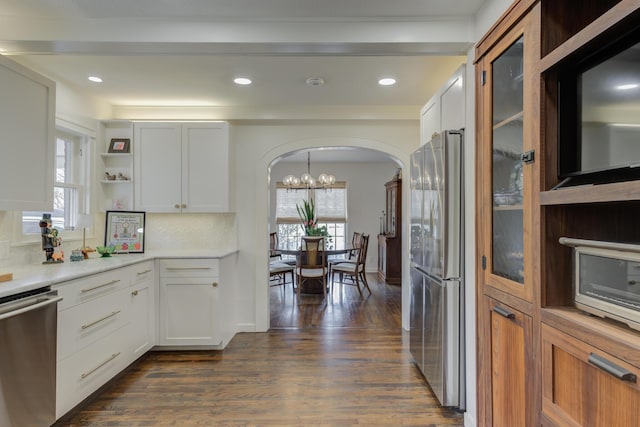 kitchen featuring a wealth of natural light, arched walkways, dark wood finished floors, and appliances with stainless steel finishes