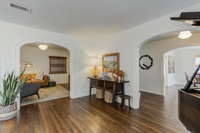 corridor with visible vents, arched walkways, and wood finished floors