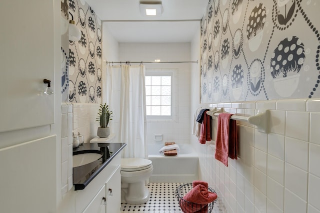 bathroom featuring toilet, vanity, shower / tub combo with curtain, and tile walls