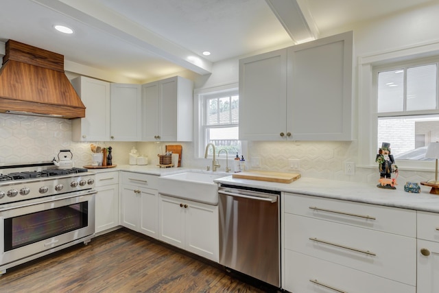 kitchen featuring custom exhaust hood, appliances with stainless steel finishes, beamed ceiling, decorative backsplash, and a sink