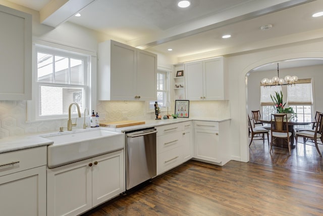 kitchen featuring stainless steel dishwasher, dark wood finished floors, arched walkways, open shelves, and a sink