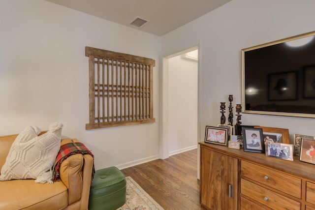 living area with dark wood-style flooring, baseboards, and visible vents