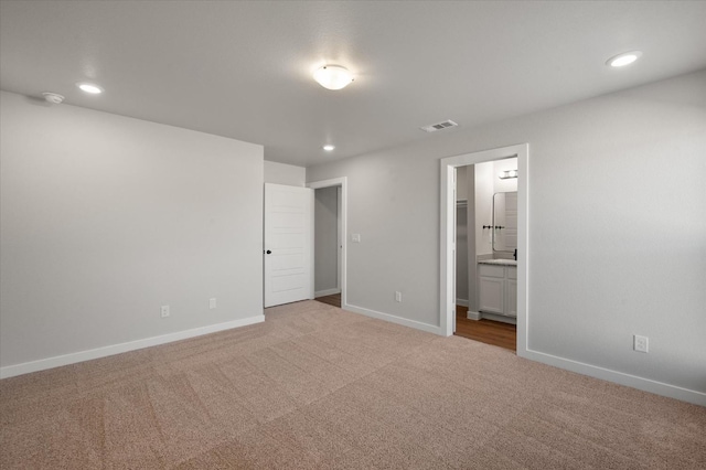 unfurnished bedroom with connected bathroom and carpet flooring