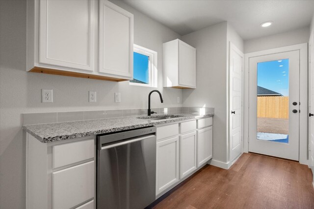 kitchen with sink, light stone counters, dark hardwood / wood-style floors, dishwasher, and white cabinets