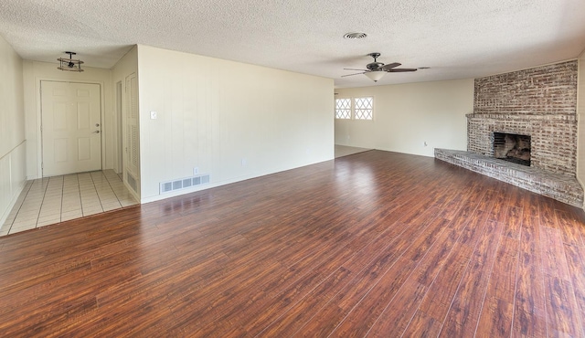 unfurnished living room with hardwood / wood-style flooring, ceiling fan, a textured ceiling, and a fireplace