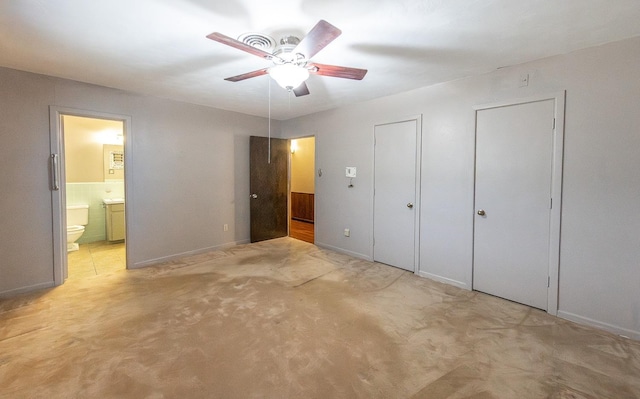 unfurnished bedroom with multiple closets, ensuite bath, ceiling fan, and light colored carpet