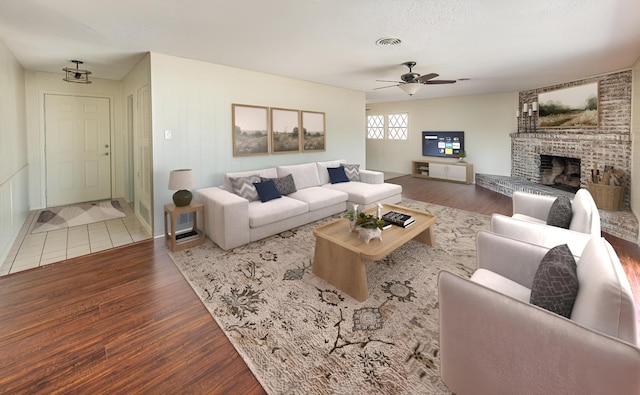 living room with hardwood / wood-style flooring, a brick fireplace, and ceiling fan