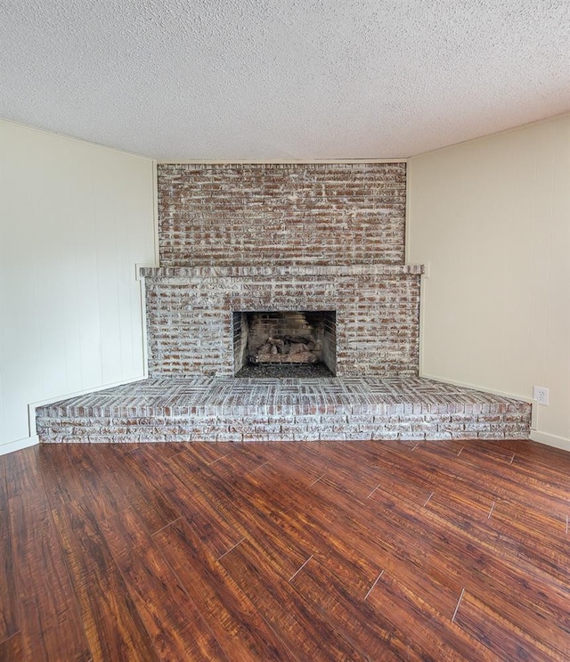 details featuring wood-type flooring, a brick fireplace, and a textured ceiling