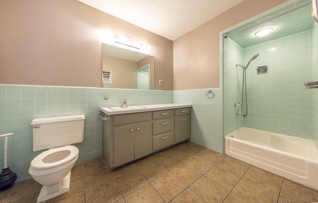 full bathroom with tiled shower / bath, tile walls, tile patterned flooring, vanity, and toilet