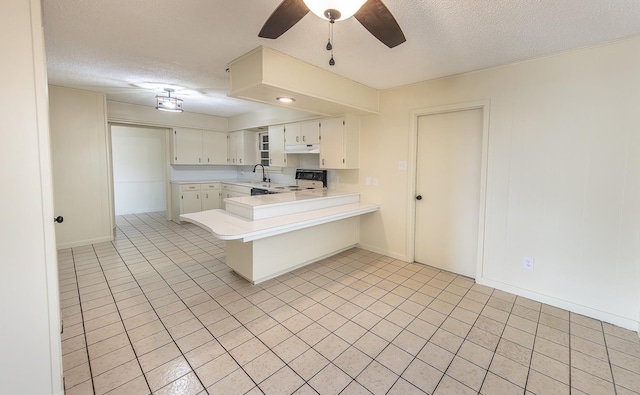 kitchen featuring sink, white cabinets, range, kitchen peninsula, and a textured ceiling