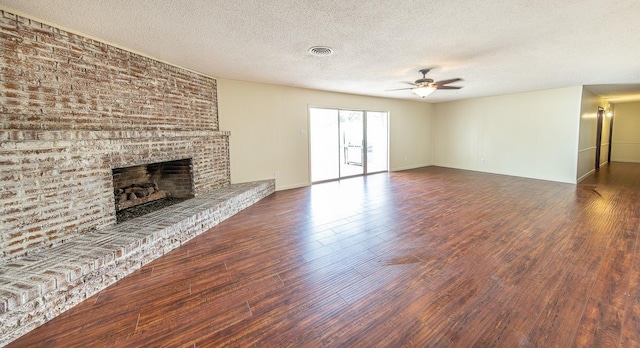 unfurnished living room featuring ceiling fan, a fireplace, dark hardwood / wood-style flooring, and a textured ceiling