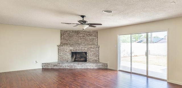 unfurnished living room with a brick fireplace, a textured ceiling, hardwood / wood-style floors, and ceiling fan