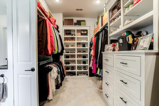 walk in closet featuring light colored carpet