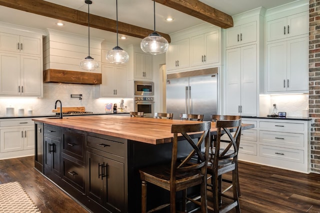 kitchen featuring a kitchen island, pendant lighting, butcher block countertops, dark hardwood / wood-style flooring, and built in appliances