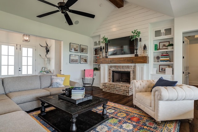 living room with a fireplace, lofted ceiling with beams, dark hardwood / wood-style flooring, ceiling fan, and french doors