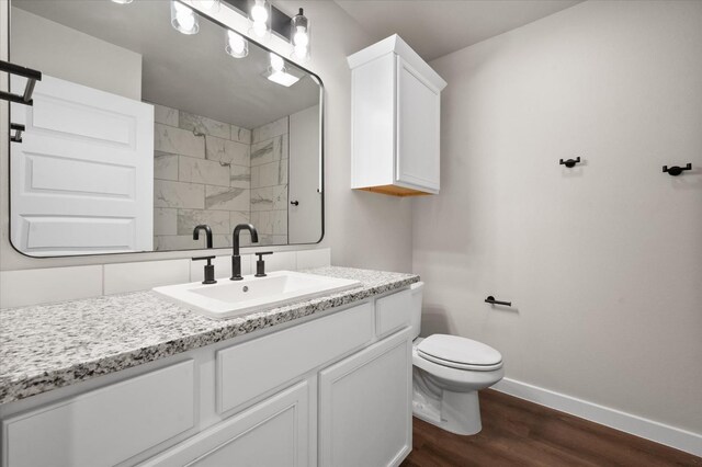 bathroom with tasteful backsplash, a shower, hardwood / wood-style flooring, vanity, and toilet