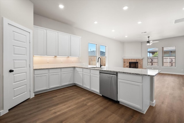 kitchen featuring dark wood-type flooring, white cabinetry, light stone counters, a brick fireplace, and dishwasher