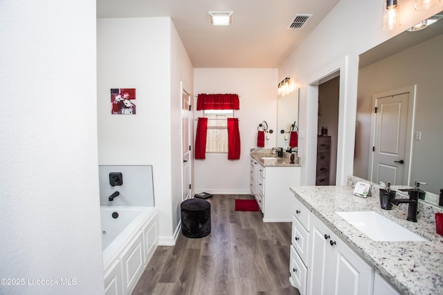 5719 117th St, Lubbock, TX 79424 - full bathroom with wood finished floors, two vanities, a bath, and baseboards