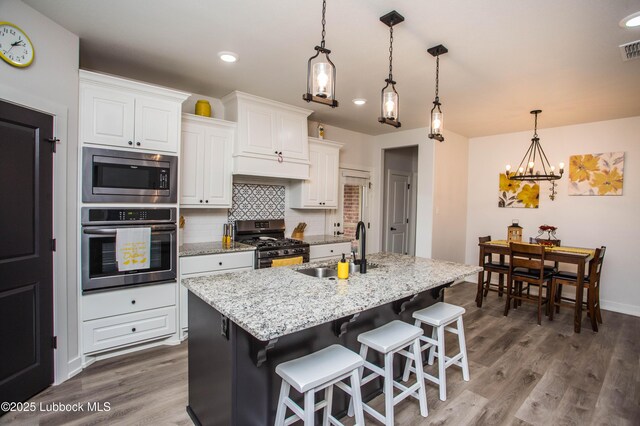 5719 117th St, Lubbock, TX 79424 - kitchen with appliances with stainless steel finishes, a sink, a chandelier, backsplash, and white cabinetry