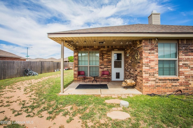 7023 35th St, Lubbock, TX 79407 - rear view of property featuring a chimney, a fenced backyard, a yard, brick siding, and a patio area