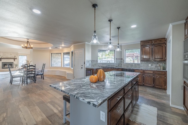 kitchen with sink, tasteful backsplash, decorative light fixtures, hardwood / wood-style flooring, and a large island