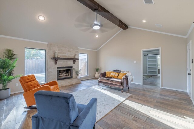 living room with ceiling fan, ornamental molding, a stone fireplace, and vaulted ceiling with beams