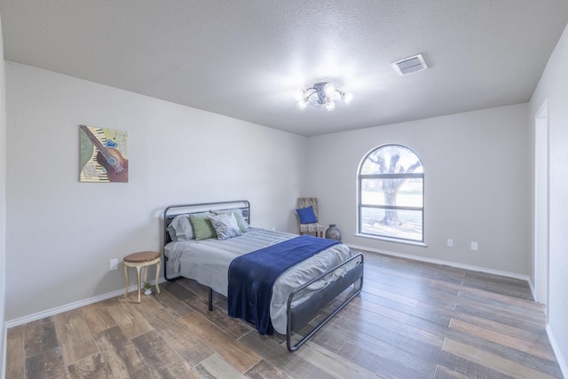 bedroom with dark hardwood / wood-style floors and a textured ceiling