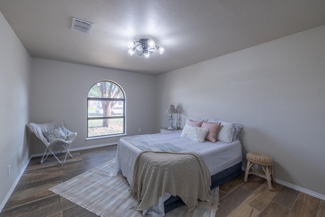 bedroom featuring a textured ceiling and dark hardwood / wood-style flooring