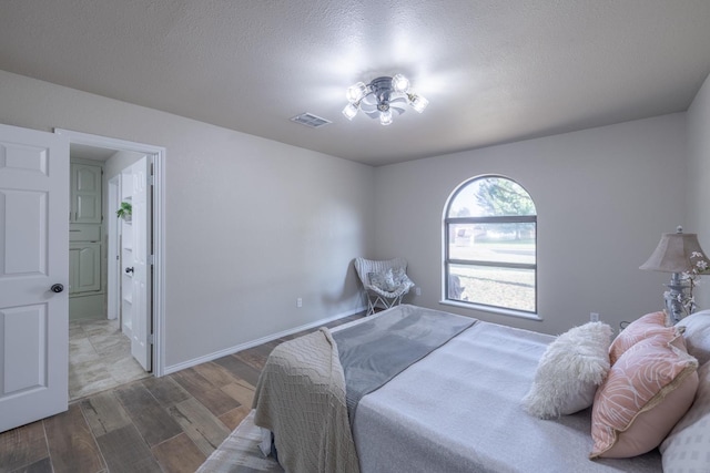 bedroom featuring hardwood / wood-style flooring, connected bathroom, and a textured ceiling