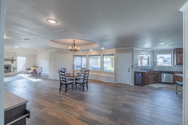 dining space with a stone fireplace, a wealth of natural light, wine cooler, and dark hardwood / wood-style flooring